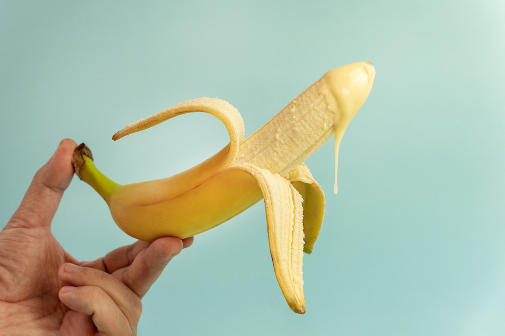banana,with,condensed,milk,in,a,man's,hand.,concept,penis