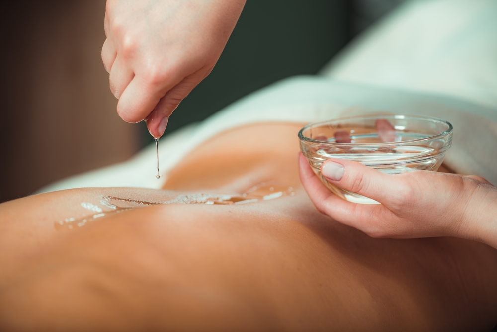 massage,oil.,therapist,pouring,aromatic,massage,oil,onto,womans,back